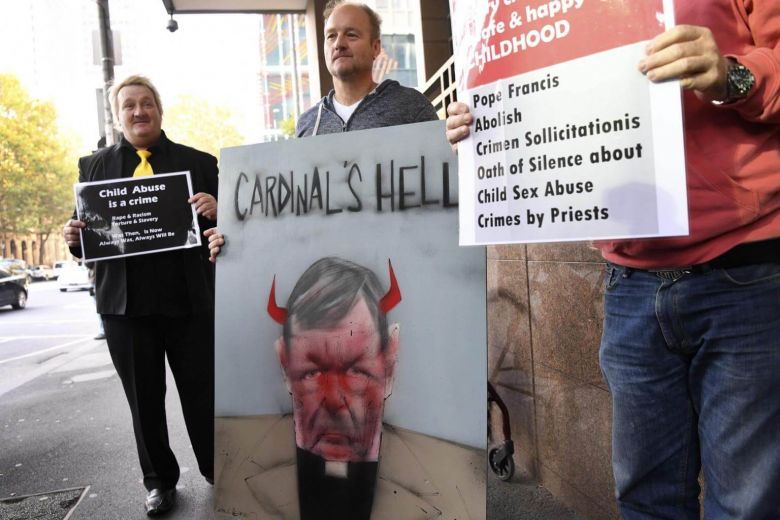 Protesters hold up placards as Vatican finance chief Cardinal George Pell arrives in court in Melbourne, on May 1, 2018